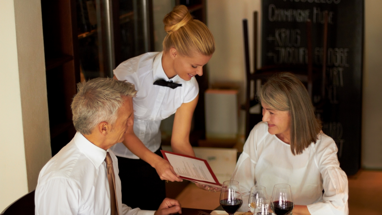 一男一女在餐廳閱讀菜單，受餐廳設計的定價策略影響